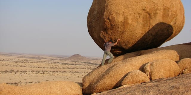 man standing beside rock formation
