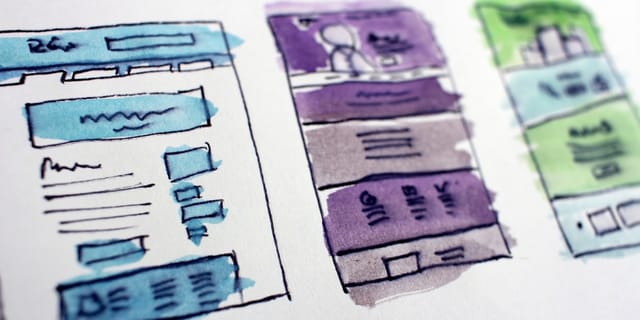 Watercolor wireframe sketches of website layouts drawn on paper