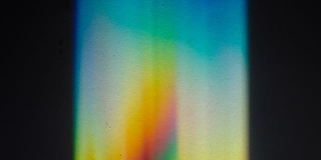 Rainbow prism light spectrum spread across a dark surface