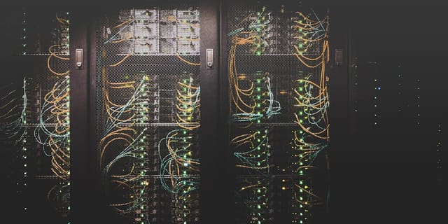Rows of server racks with cabling in a modern data center aisle.