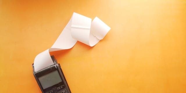 Payment terminal with printed receipt rolling out on orange background