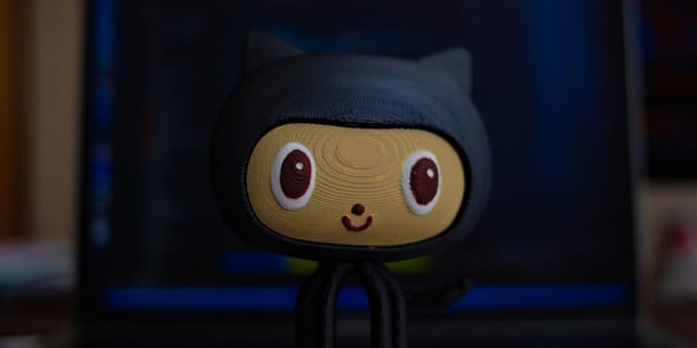 Tux penguin figurine in front of a laptop showing a code editor and terminal