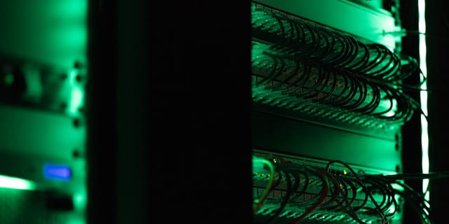 A rack of electronic equipment in a dark data center room, lit by indicator LEDs — the kind of infrastructure serving the DeepSeek V4 Flash API