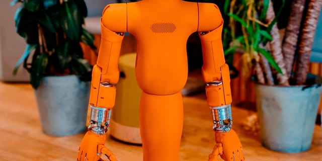 A friendly orange humanoid robot with a digital screen for a face
