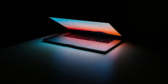 A dark terminal window filled with source code and shell commands on a laptop