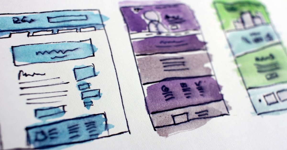 Watercolor wireframe sketches of website layouts drawn on paper