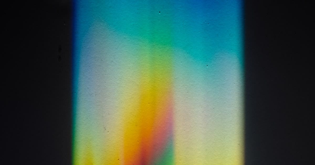 Rainbow prism light spectrum spread across a dark surface