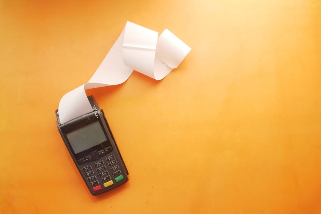 Payment terminal with printed receipt rolling out on orange background