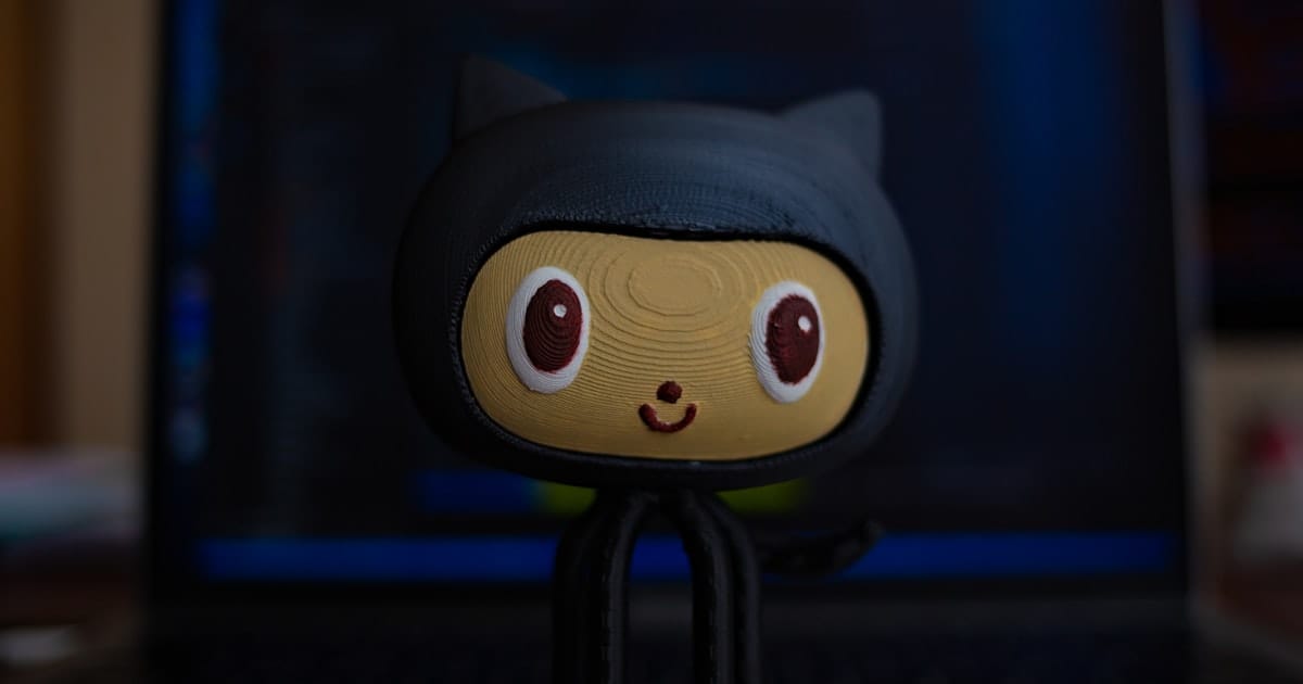 Tux penguin figurine in front of a laptop showing a code editor and terminal