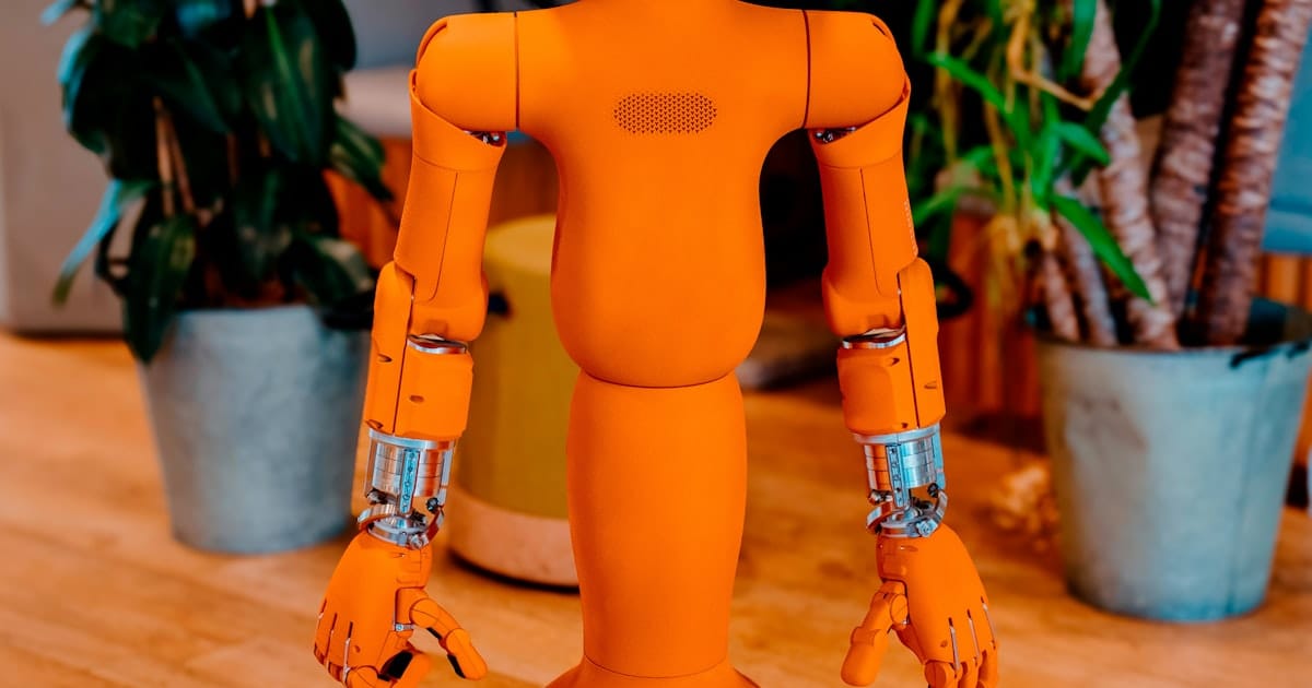 A friendly orange humanoid robot with a digital screen for a face